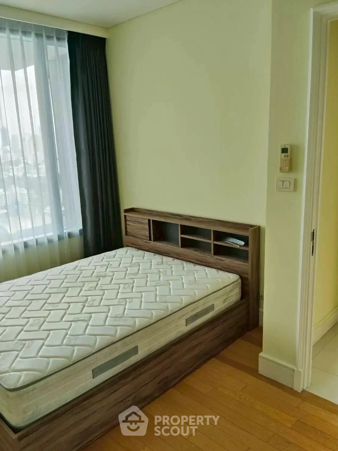 Cozy bedroom with large window and wooden flooring, featuring a comfortable bed and modern design.