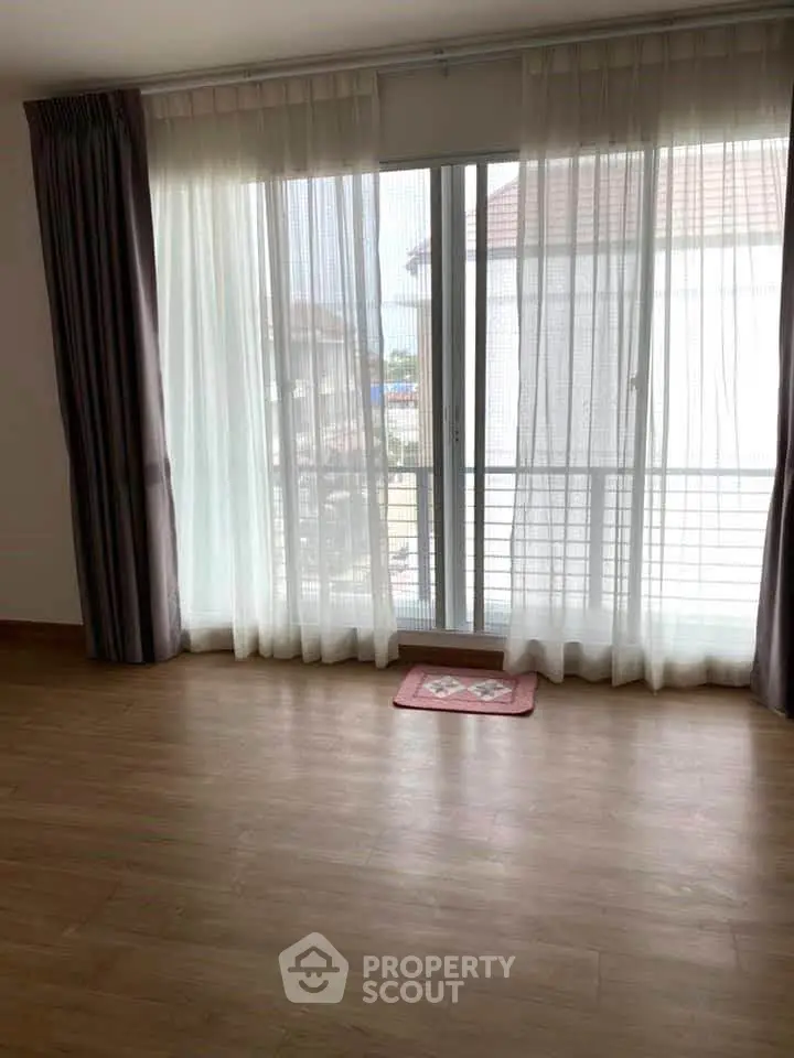 Spacious living room with large windows and wooden flooring, offering ample natural light.