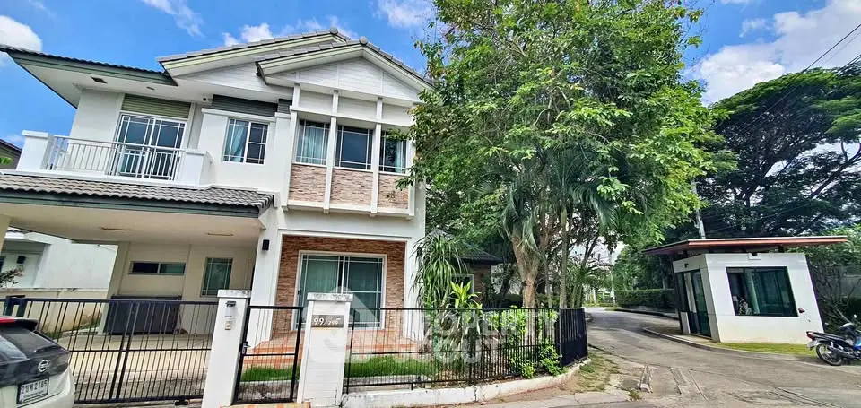 Charming two-story house with lush garden and gated entrance in a serene neighborhood.