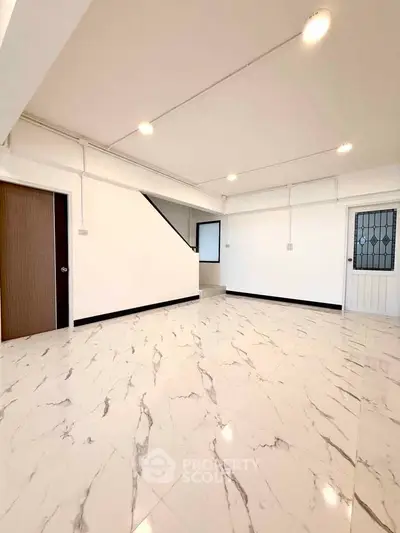 Spacious interior with marble flooring and modern lighting, ideal for versatile living space.