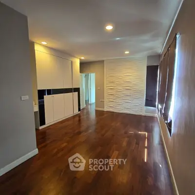 Spacious modern living room with elegant wooden flooring and stylish wall design.