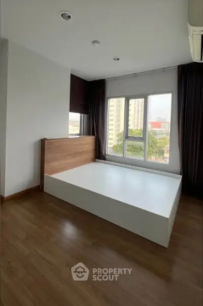 Spacious bedroom with large window offering city views and modern wooden flooring.