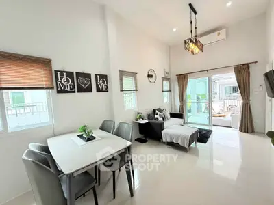 Modern living room with stylish decor and open layout, featuring a cozy dining area and large windows for natural light.