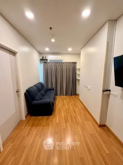 Spacious living room with wooden flooring and modern furnishings in a stylish apartment.