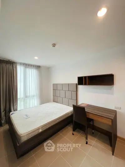 Modern bedroom with natural light, featuring a bed and study desk, ideal for comfortable living.