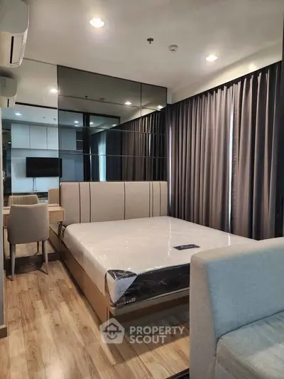 Modern bedroom with mirrored wall, cozy bed, and elegant wooden flooring in a stylish apartment.