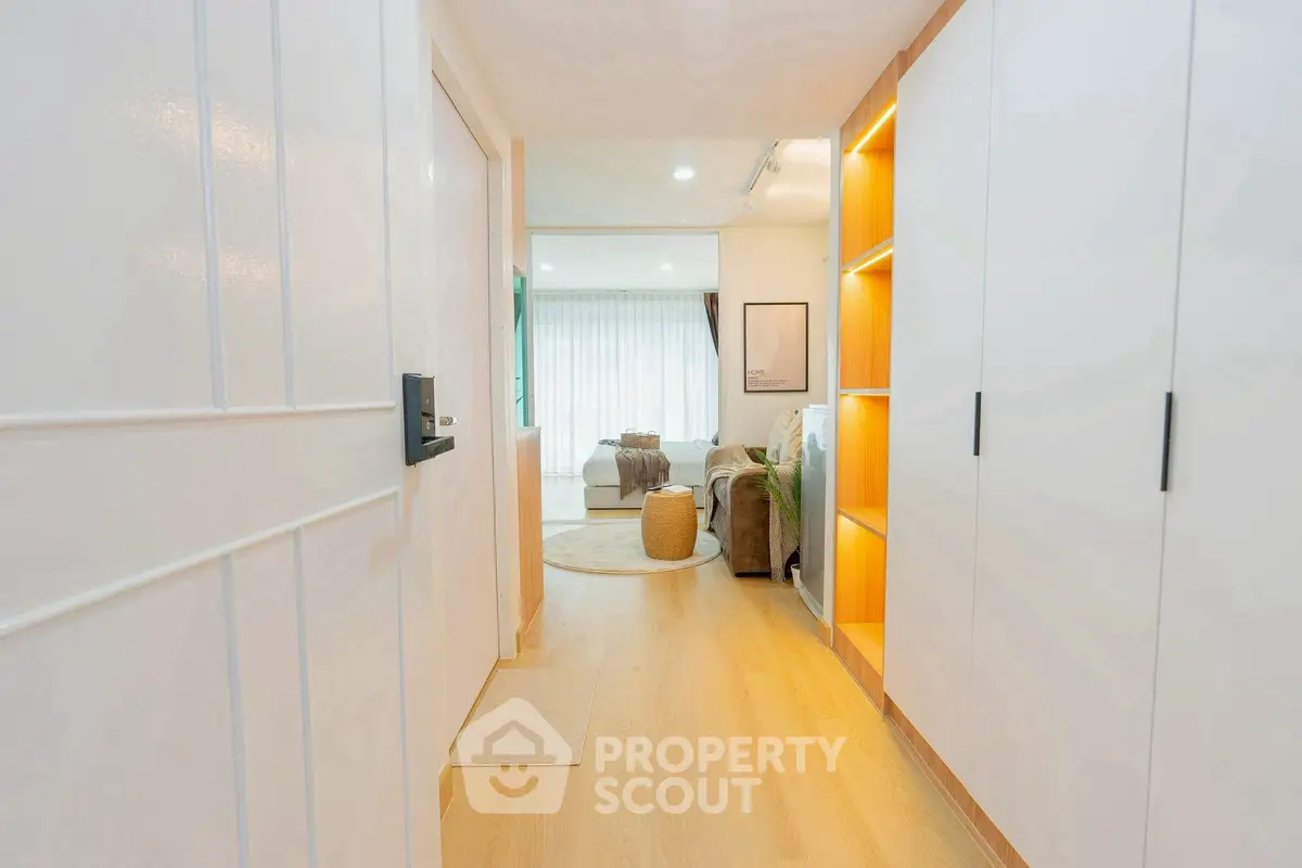 Bright hallway leading to a cozy living room with modern decor and ample natural light.