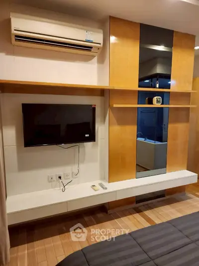 Modern bedroom with wall-mounted TV and air conditioning, featuring sleek wooden paneling and stylish decor.