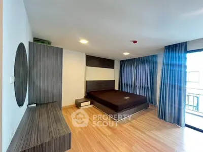 Spacious modern bedroom with wooden flooring and large windows for natural light.