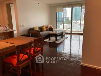 Spacious living room with hardwood floors and city view balcony in modern apartment.