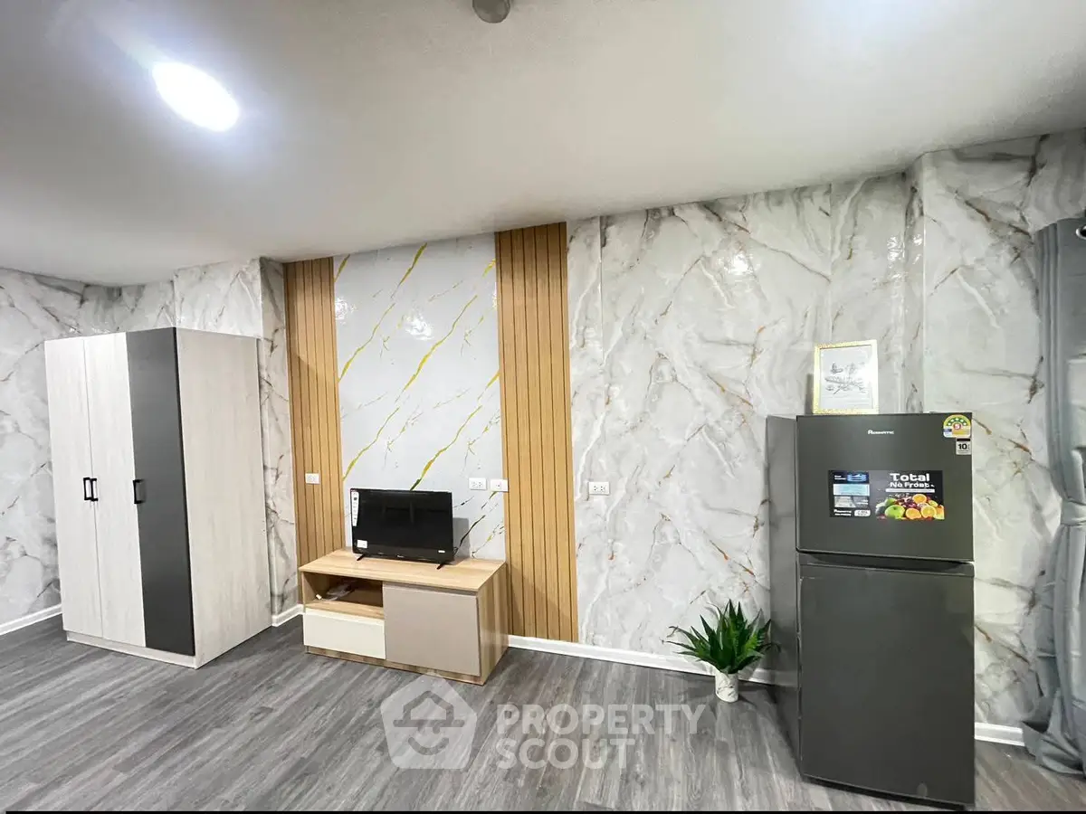 Modern living room with stylish marble walls and sleek furniture, featuring a refrigerator and entertainment unit.
