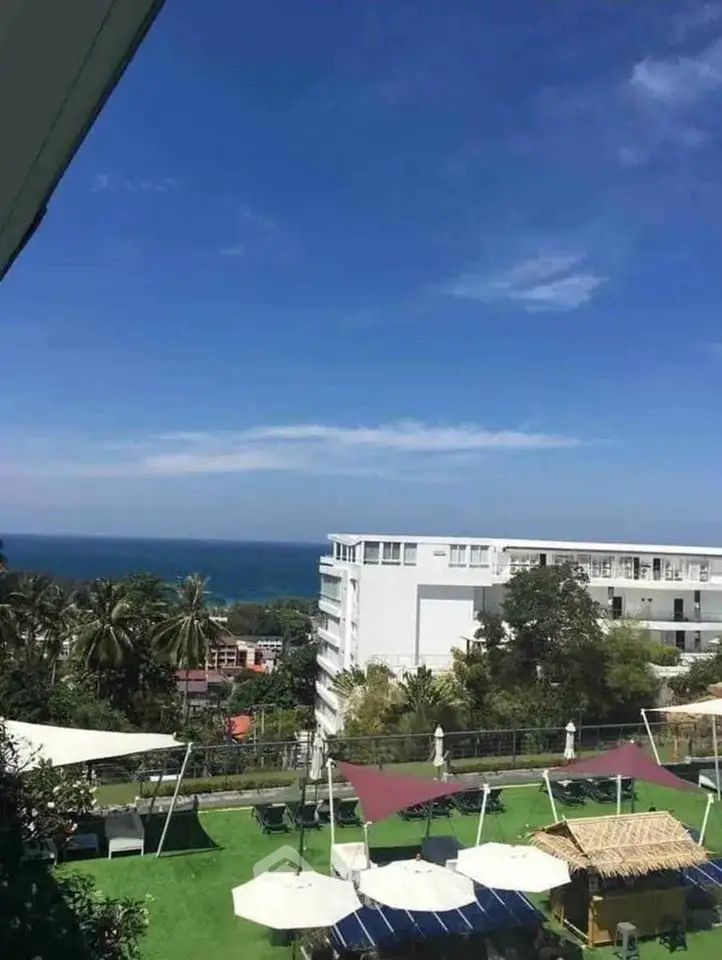 Stunning ocean view from a modern building with lush green garden and shaded seating area.