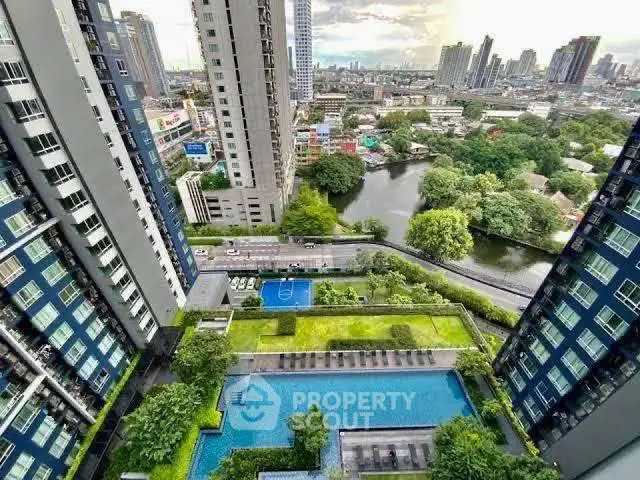 Stunning aerial view of modern high-rise buildings with lush gardens and a sparkling pool in a vibrant cityscape.
