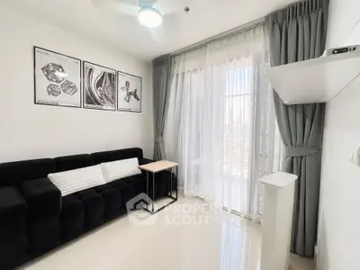Modern living room with sleek black sofa, elegant curtains, and stylish wall art.