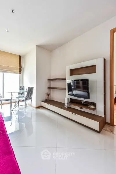 Modern living room with sleek TV unit and dining area, bright and spacious.