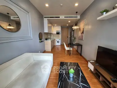 Modern living room with open kitchen, stylish decor, and wooden flooring.