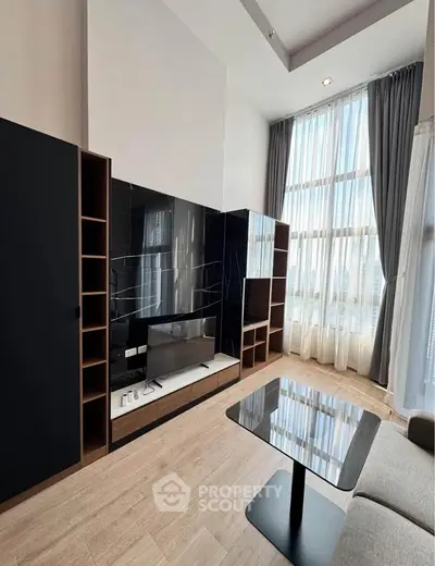 Modern living room with high ceilings, large windows, and sleek black entertainment center.