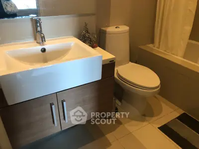 Modern bathroom with sleek sink and toilet, featuring a bathtub and elegant fixtures.
