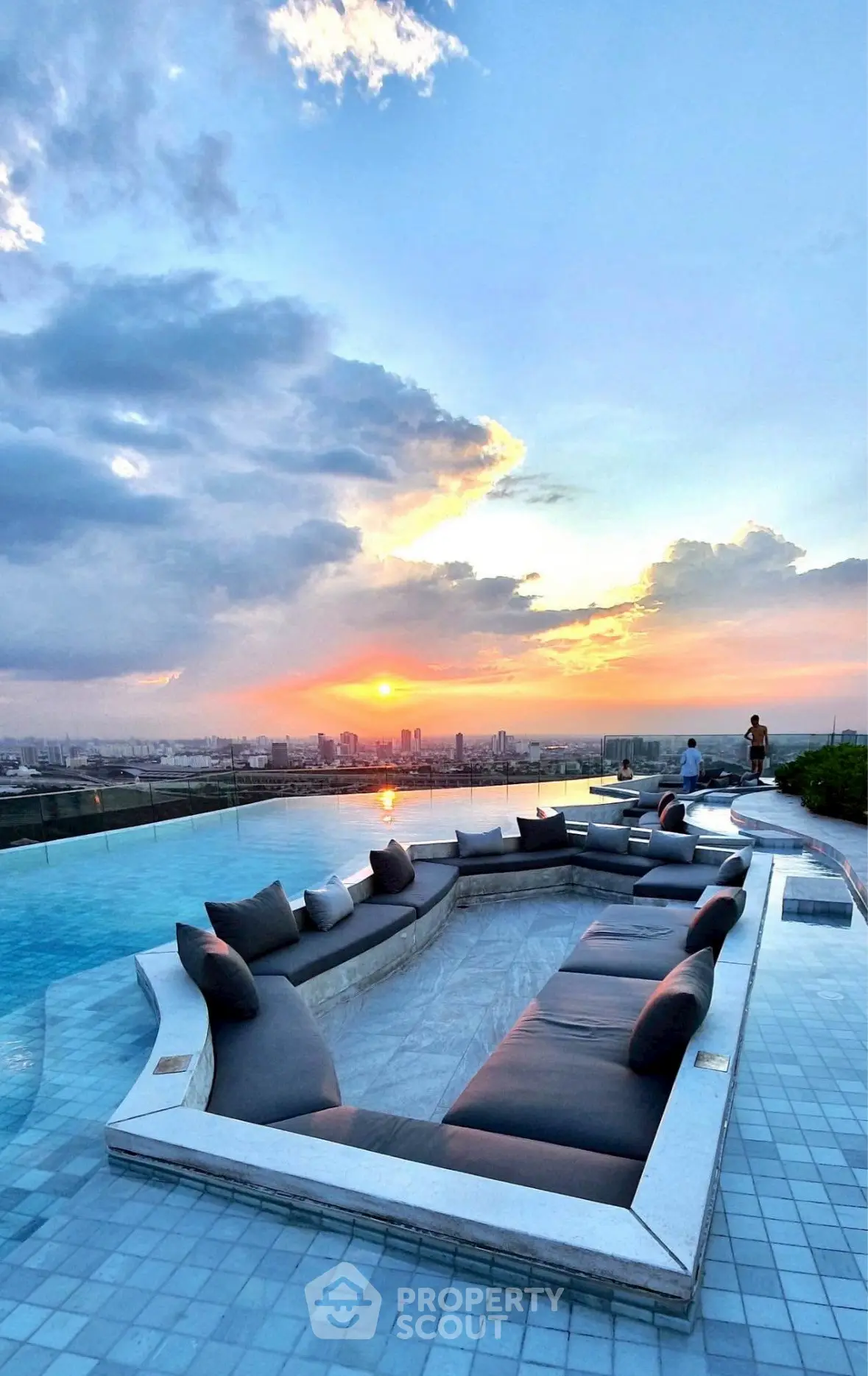 Luxurious rooftop pool with stunning sunset city view and elegant seating area.