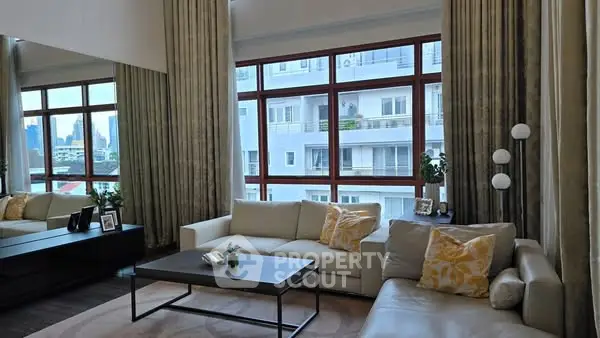Spacious living room with large windows and modern decor in urban apartment.