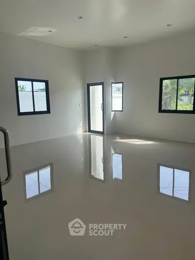 Spacious empty room with glossy tiled floor and large windows for natural light.