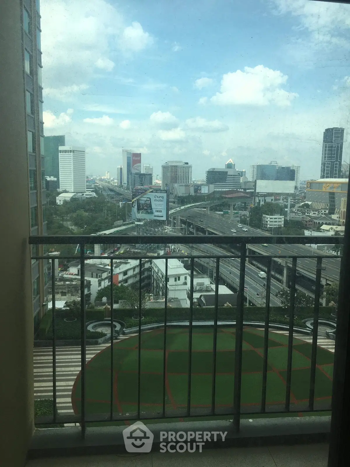 Stunning cityscape view from a high-rise balcony overlooking urban skyline and highways.