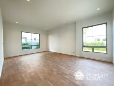 Spacious and bright living room with large windows offering an abundance of natural light and serene garden views, perfect for modern living.