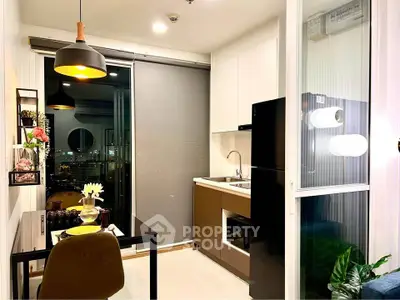 Modern kitchen with sleek design and city view, featuring black fridge and stylish lighting.