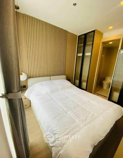 Modern bedroom with stylish wood paneling and ensuite bathroom in a cozy apartment.