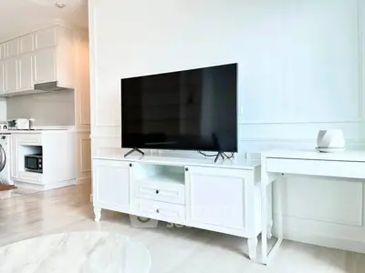 Modern living room with sleek TV setup and stylish white furniture in a bright apartment.