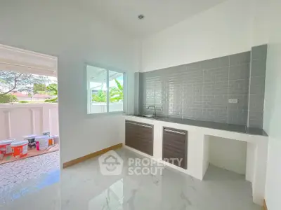 Modern kitchen with sleek cabinetry and tiled backsplash, adjacent to a bright balcony area.