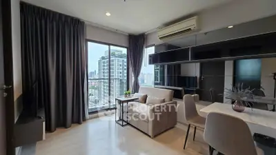 Modern living room with city view, featuring sleek furniture and large windows for natural light.