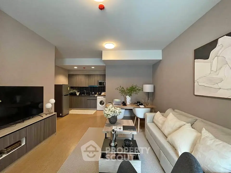Modern living room with open kitchen, stylish decor, and cozy seating area in a contemporary apartment.