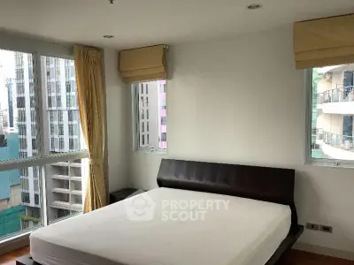 Spacious bedroom with large windows offering city views in modern apartment.