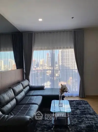 Modern living room with city view, black leather sofa, and stylish decor