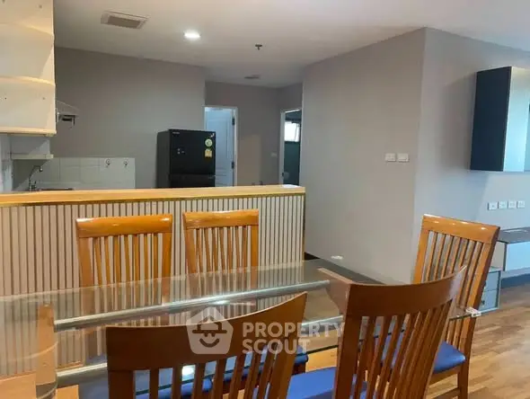 Spacious dining area with wooden furniture and modern kitchen in open layout apartment.