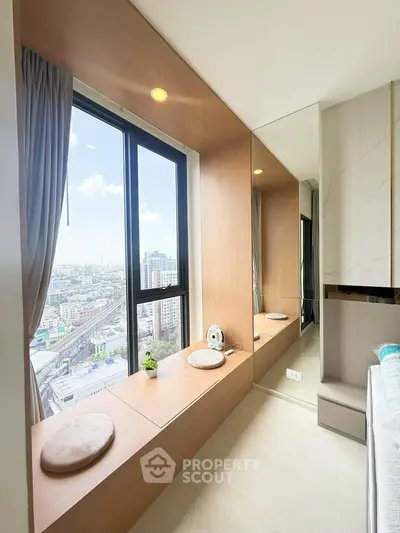 Modern bedroom with panoramic city view and cozy seating area by the window.
