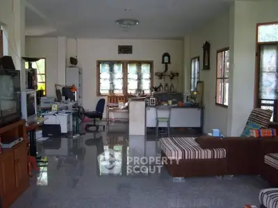 Spacious living room with modern decor and natural light, featuring a cozy seating area and home office setup.
