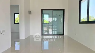 Spacious modern living room with large windows and sliding glass door, offering abundant natural light.