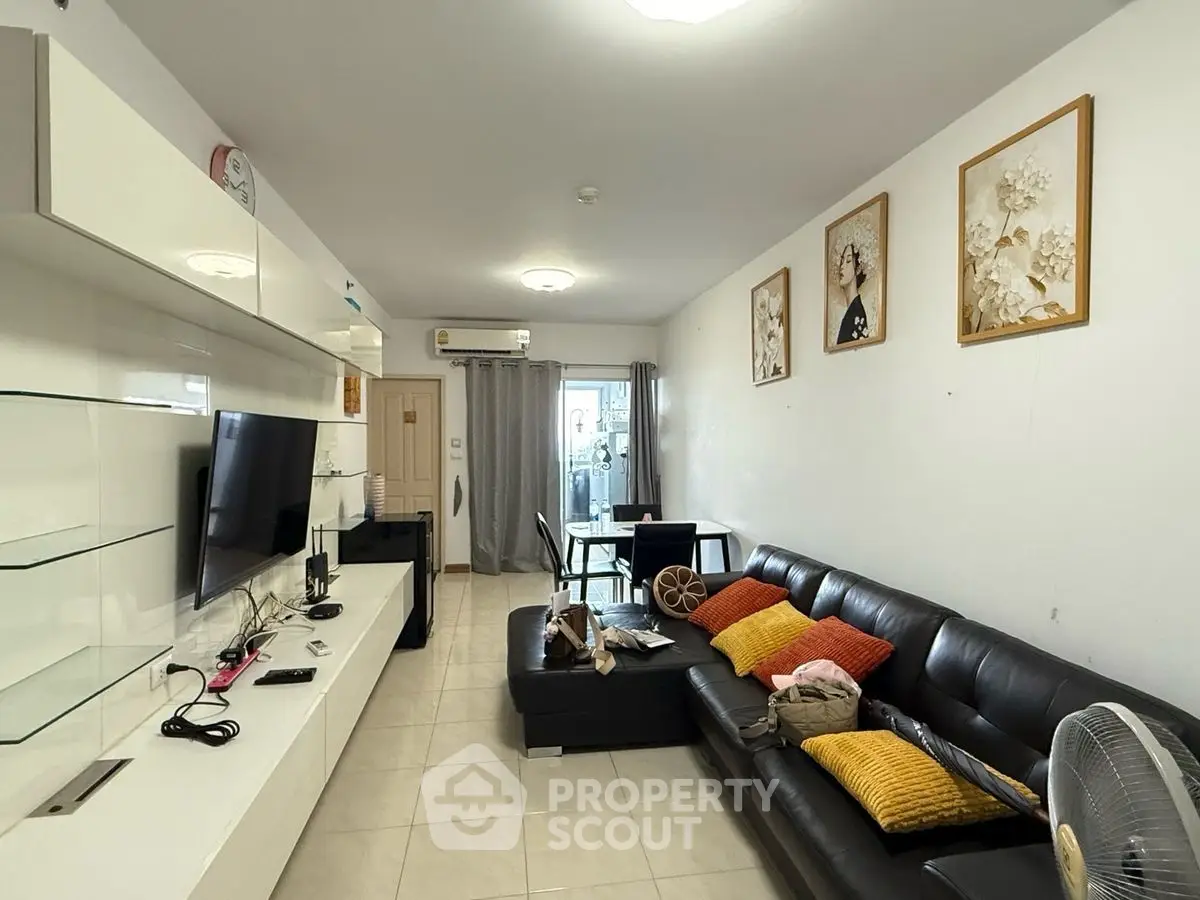Modern living room with sleek black sofa and wall-mounted TV, perfect for relaxation.
