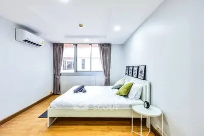 Spacious bedroom with modern decor and natural light in a stylish apartment.