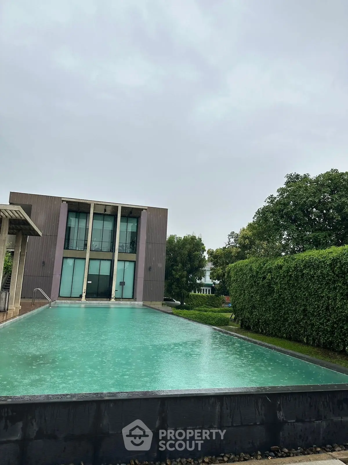 Luxurious modern building with a stunning pool and lush greenery, perfect for relaxation and leisure.