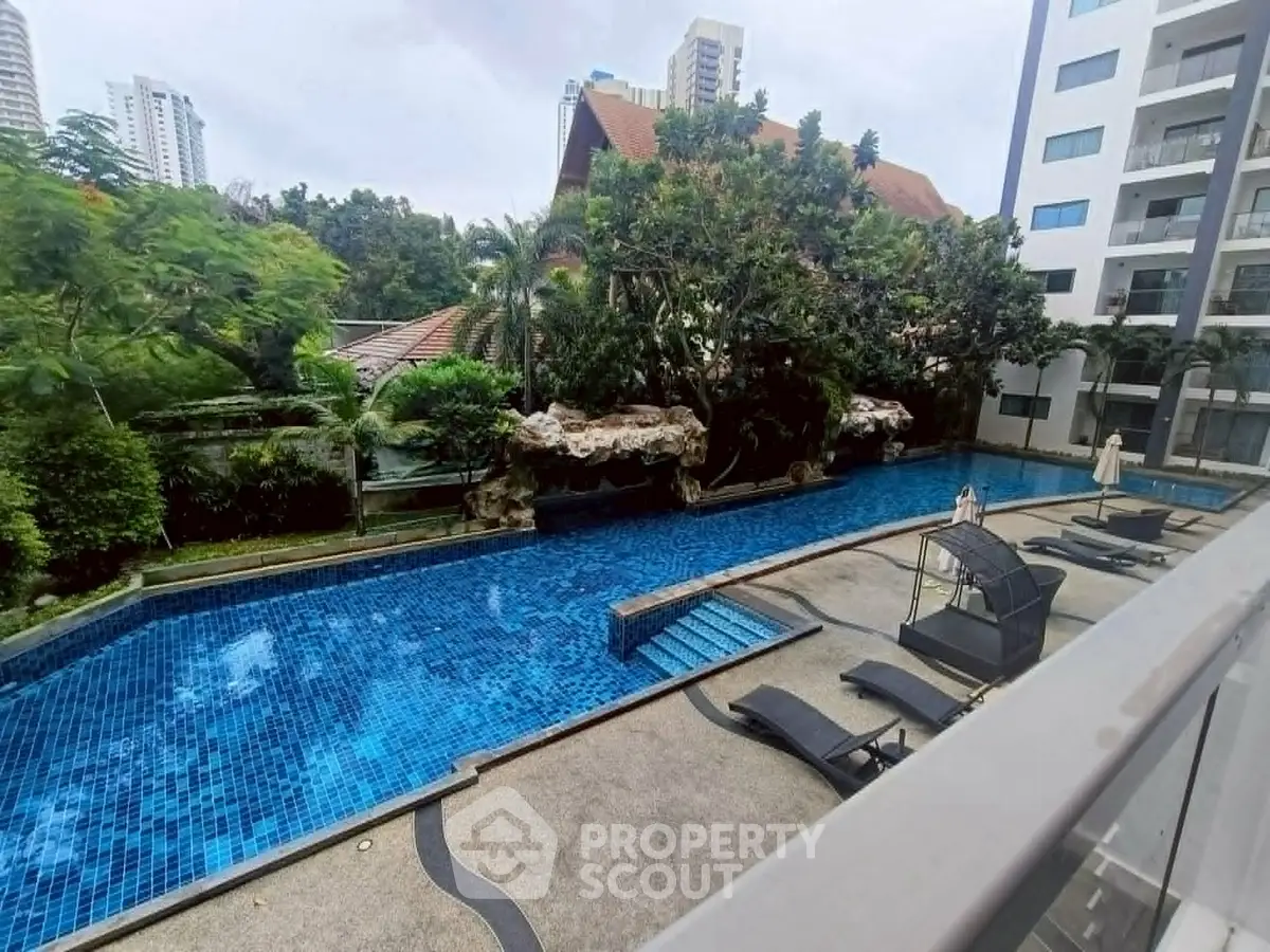 Luxurious condominium pool area with lush greenery and modern amenities, perfect for relaxation and leisure.