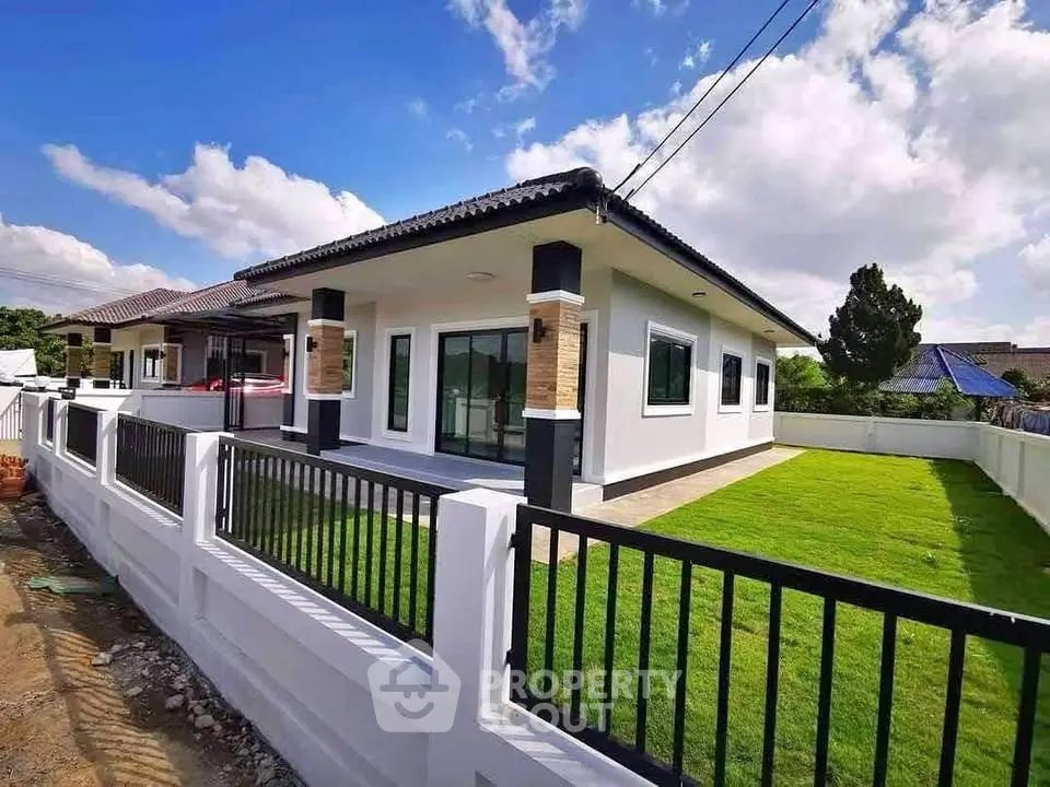 Modern single-story house with spacious lawn and sleek fence design.