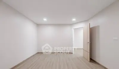 Spacious empty room with wooden flooring and open door, ideal for customization.