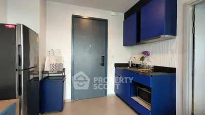 Modern kitchen with blue cabinets and stainless steel appliances in a stylish apartment.
