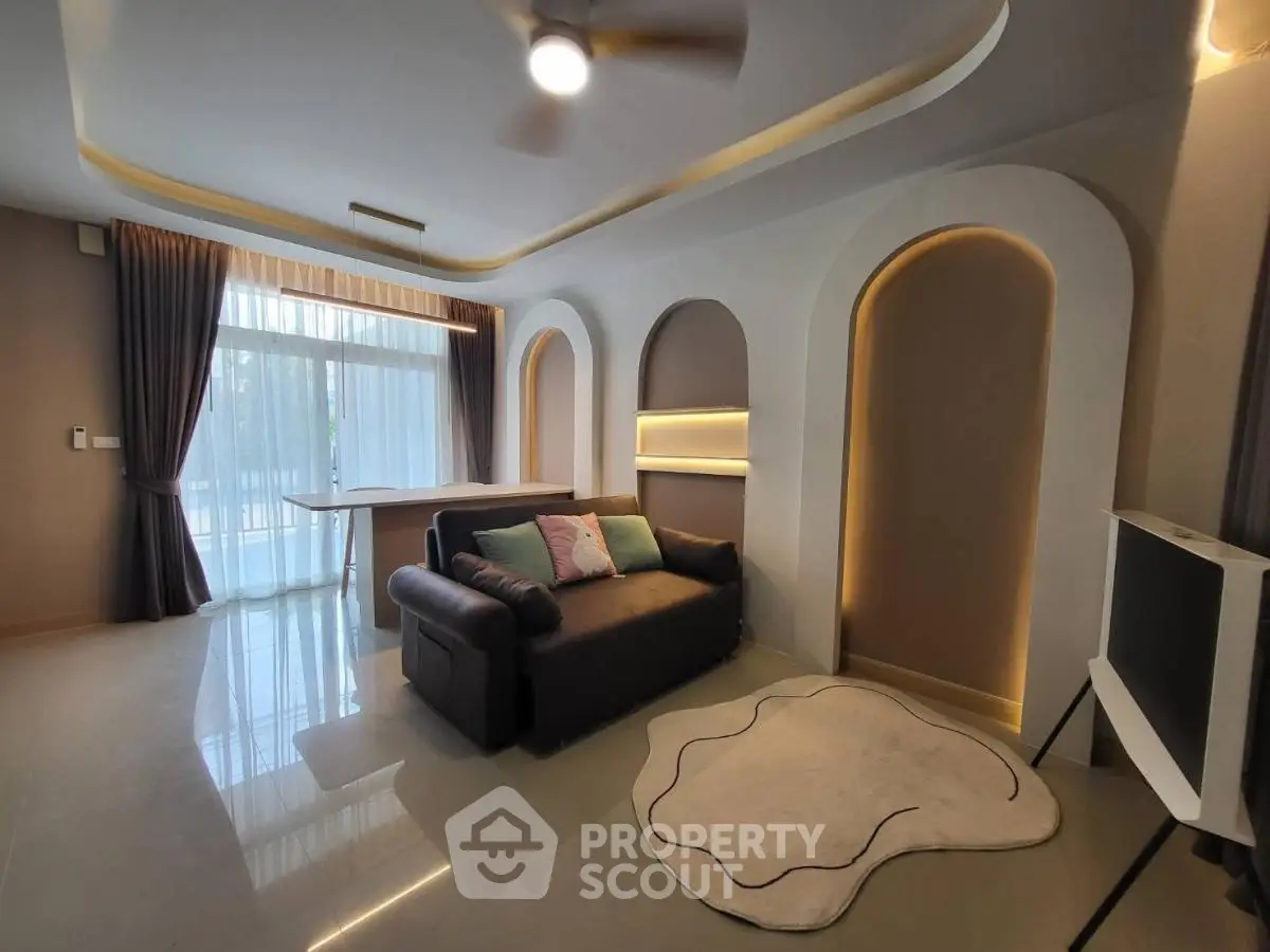 Modern living room with stylish lighting and cozy sofa, featuring large windows and elegant decor.