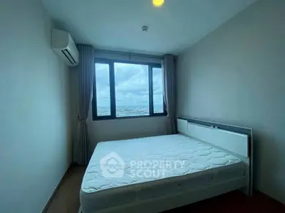 Modern bedroom with large window offering stunning city view and natural light.