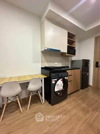 Modern compact kitchen with dining area, featuring sleek appliances and stylish wooden flooring.