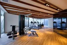 Modern gym with state-of-the-art equipment and wooden flooring in luxury apartment building.